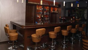 A bar area with a long counter, multiple stools, and a variety of bottles on shelves. - Hotel Filoxenia (Chania)