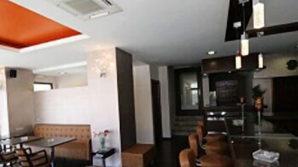 A modern restaurant interior with high tables and chairs, a bar area, and a seating section with cushioned benches. - Hotel Filoxenia (Chania)