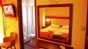 A hotel room with a bed, a television, a mirror, and a chair. - Hotel Filoxenia (Chania)