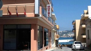 A hotel with a prominent sign, a balcony with flags, and a view of the sea. - Hotel Filoxenia (Chania)