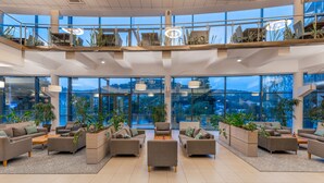 A spacious lobby with multiple seating areas, large windows offering views of the outdoors, and a modern architectural design. - Hotel Krynica Conference & SPA (Krynica-Zdroj)