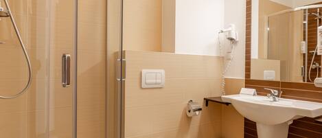 A modern bathroom with a glass-enclosed shower, a white toilet, and a sink with a mirror above it.