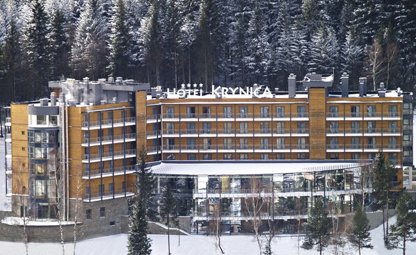 Ein mehrstöckiges Hotel mit einem gut sichtbaren Schild, auf dem "HOTEL KRYNA" steht.
