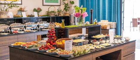 A buffet with various food items and a decorative vase with flowers.