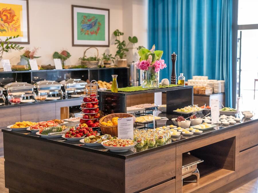 A buffet with various food items and a decorative vase with flowers.