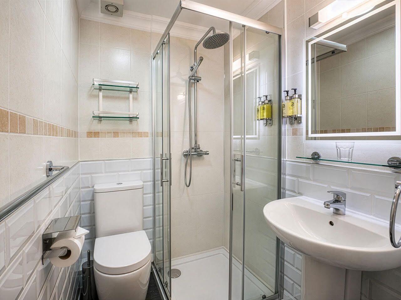 Une salle de bain moderne avec une douche à parois de verre, des toilettes blanches, un lavabo et un miroir.