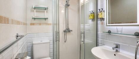 Une salle de bain moderne avec une douche à parois de verre, des toilettes blanches, un lavabo et un miroir.