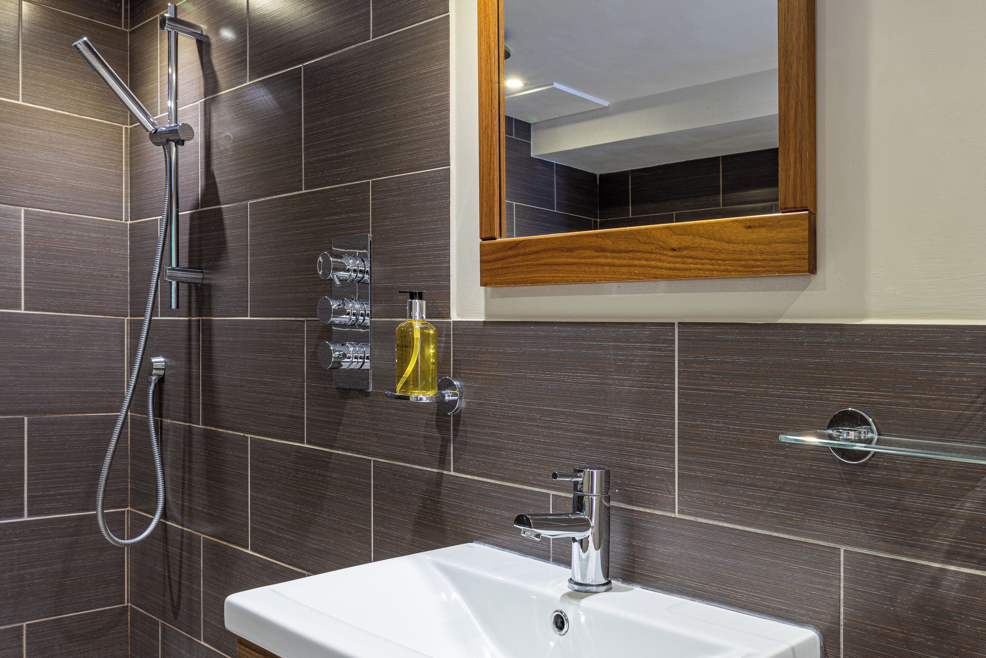 A modern bathroom with a white sink, chrome faucet, and a handheld showerhead.