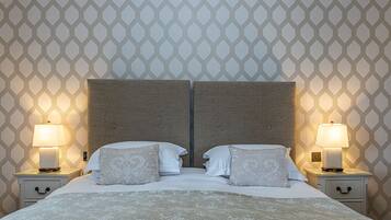 A double bed with a headboard, two bedside tables with lamps, and a patterned wallpaper.