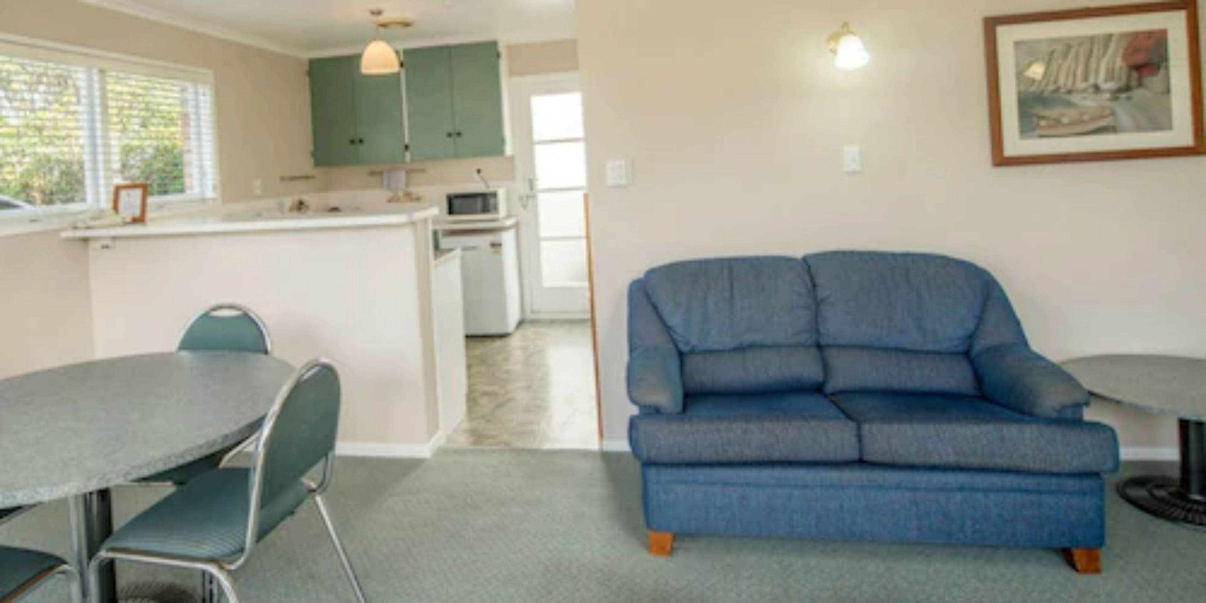 Un espacio habitable compacto con kitchenette, comedor y sofá.