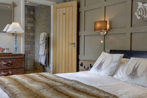 A bedroom with a wooden door, a bedside lamp, a fluffy blanket, and decorative pillows. - Beck Hall (Skipton)