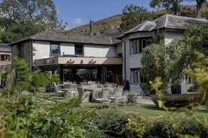 A building with a patio area featuring wicker furniture and a large planter. - Beck Hall (Skipton)