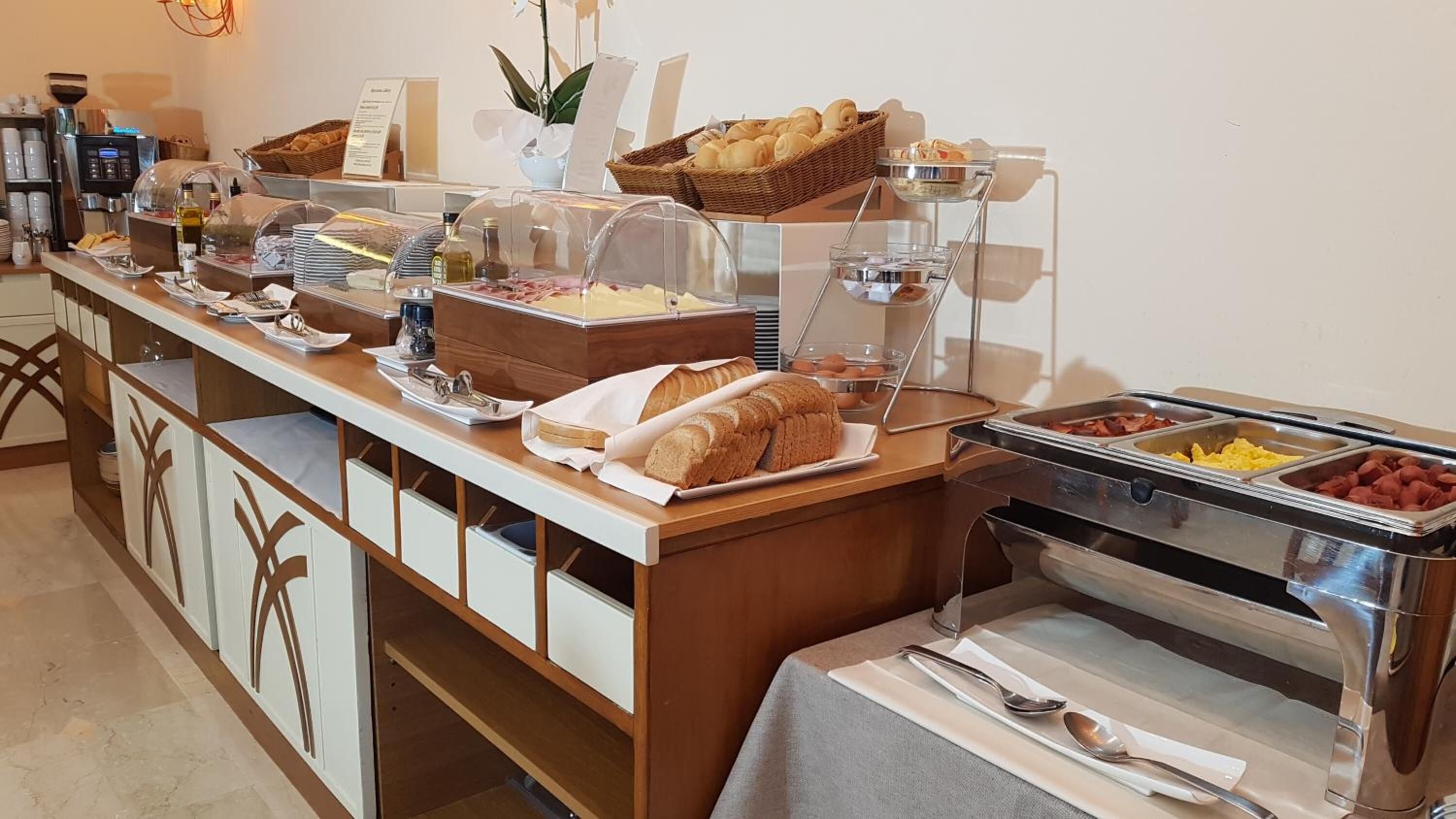 Montaje de bufé con diversos alimentos, como pan, pasteles y frutas.