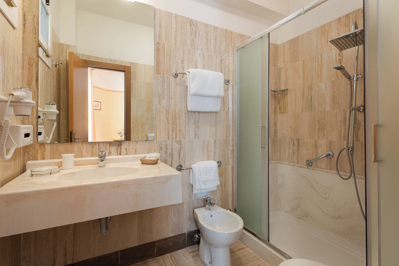 A modern bathroom with a marble vanity, a glass shower enclosure, and a bidet.