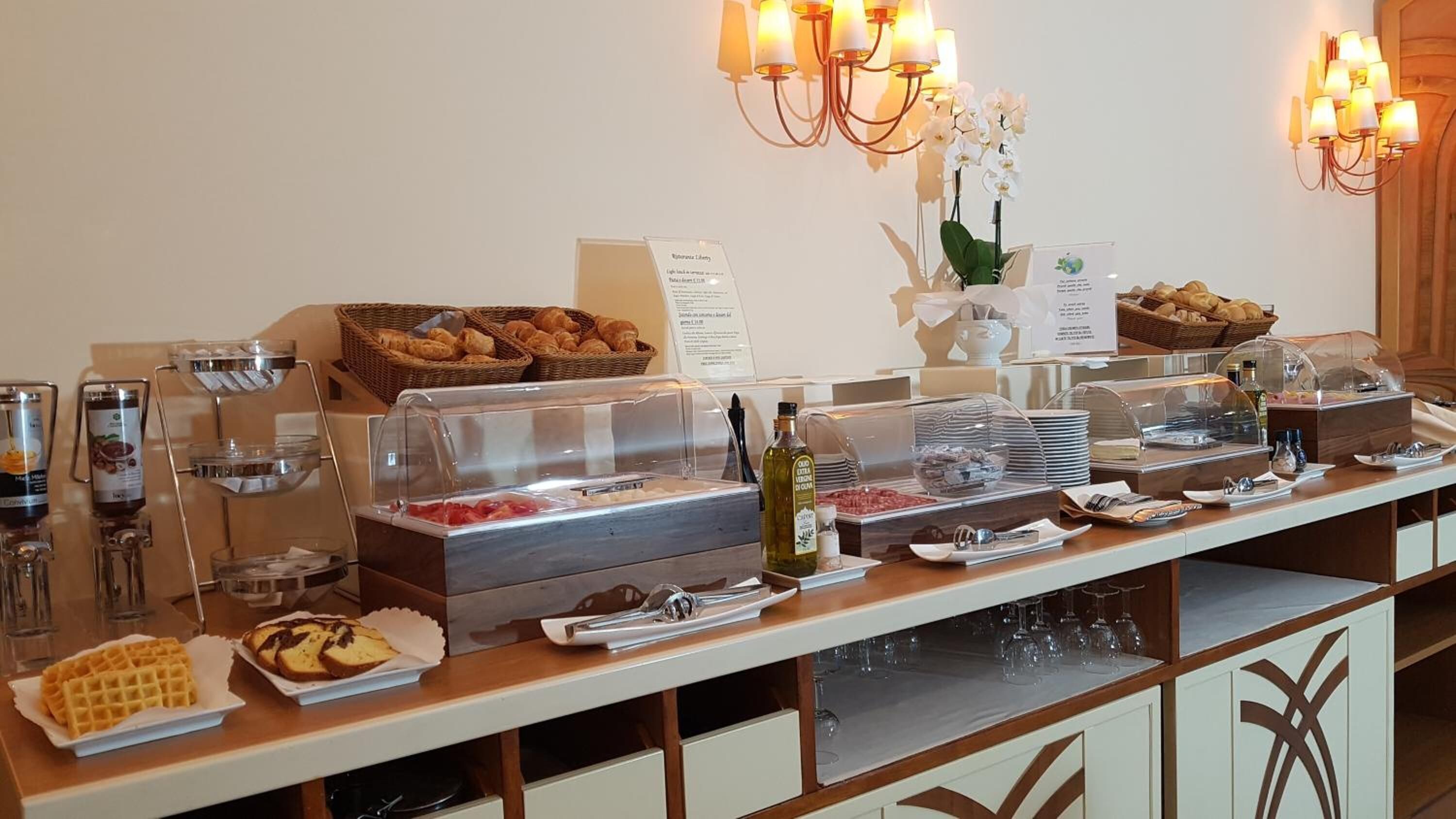 A buffet setup with various food items, including bread, pastries, and a selection of beverages.