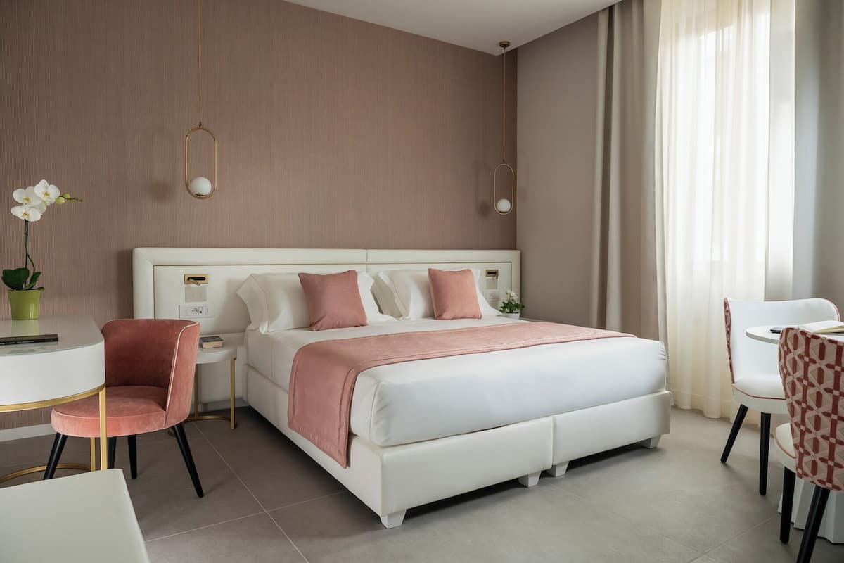 A modern hotel room with a large bed, a desk, and a chair.