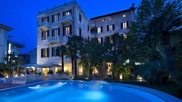 A multi-story hotel with a swimming pool, surrounded by greenery and evening lighting. - Hotel Parma e Oriente Wellness & Spa (Montecatini Terme)