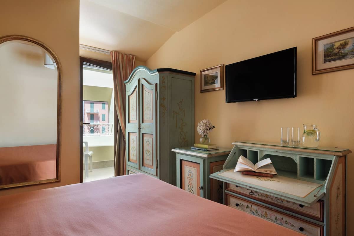 A bedroom with a bed, a television, a cabinet, and a window with curtains.