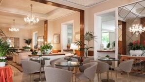 A modern hotel lobby with round tables, comfortable seating, and decorative lighting. - Hotel Parma e Oriente Wellness & Spa (Montecatini Terme)