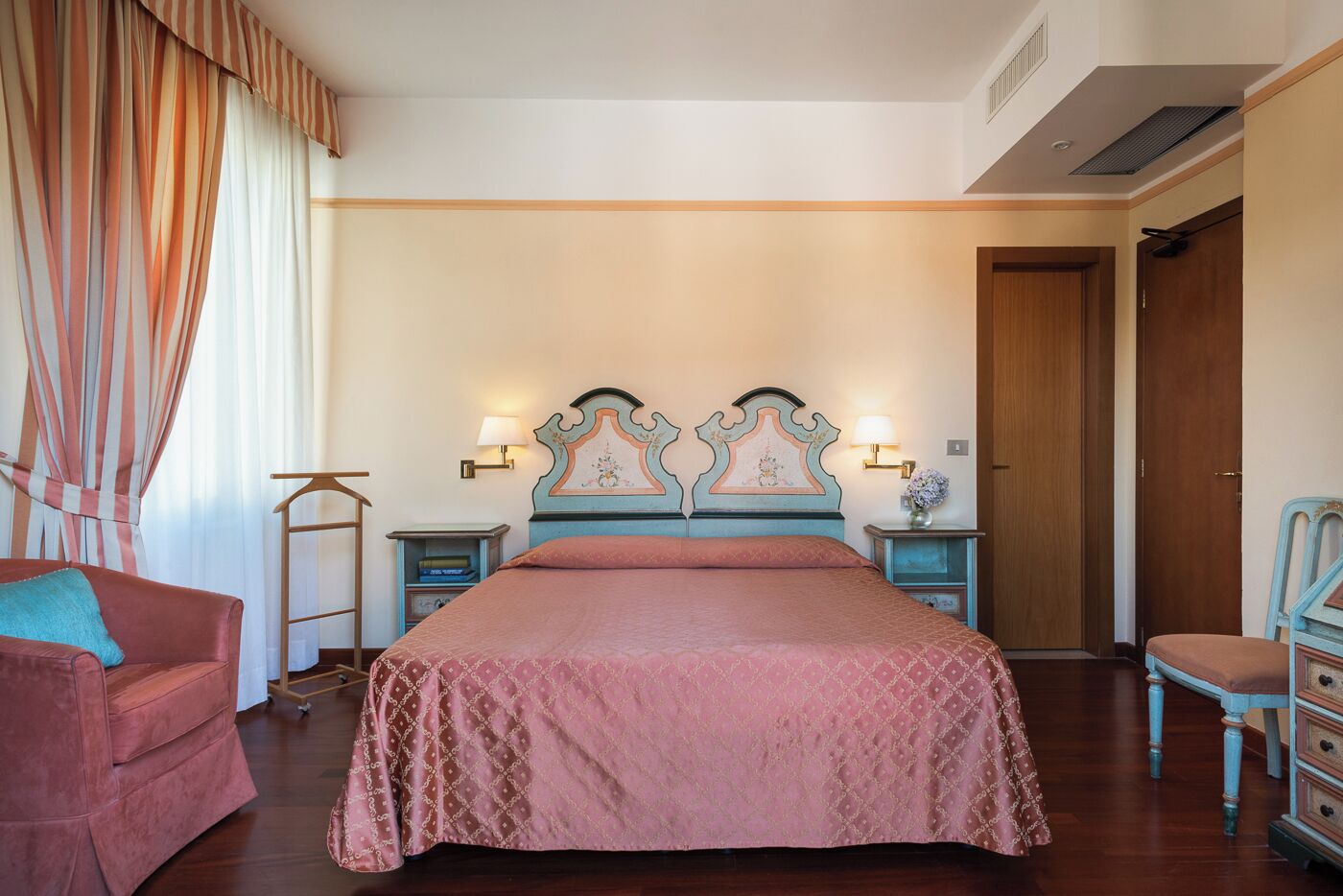 A bedroom with a large bed, two bedside tables, a chair, and a wardrobe.