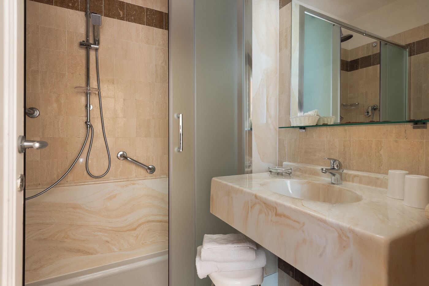 Een moderne badkamer met een douche, wastafel en spiegel.