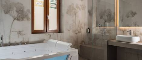 Ein modernes Badezimmer mit einer großen Badewanne, einer Glasdusche und einem Waschbecken mit Spiegel.