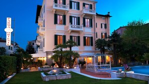 A multi-story hotel with a well-maintained garden, outdoor seating, and a visible sign reading "PARMA ORIENTE". - Hotel Parma e Oriente Wellness & Spa (Montecatini Terme)