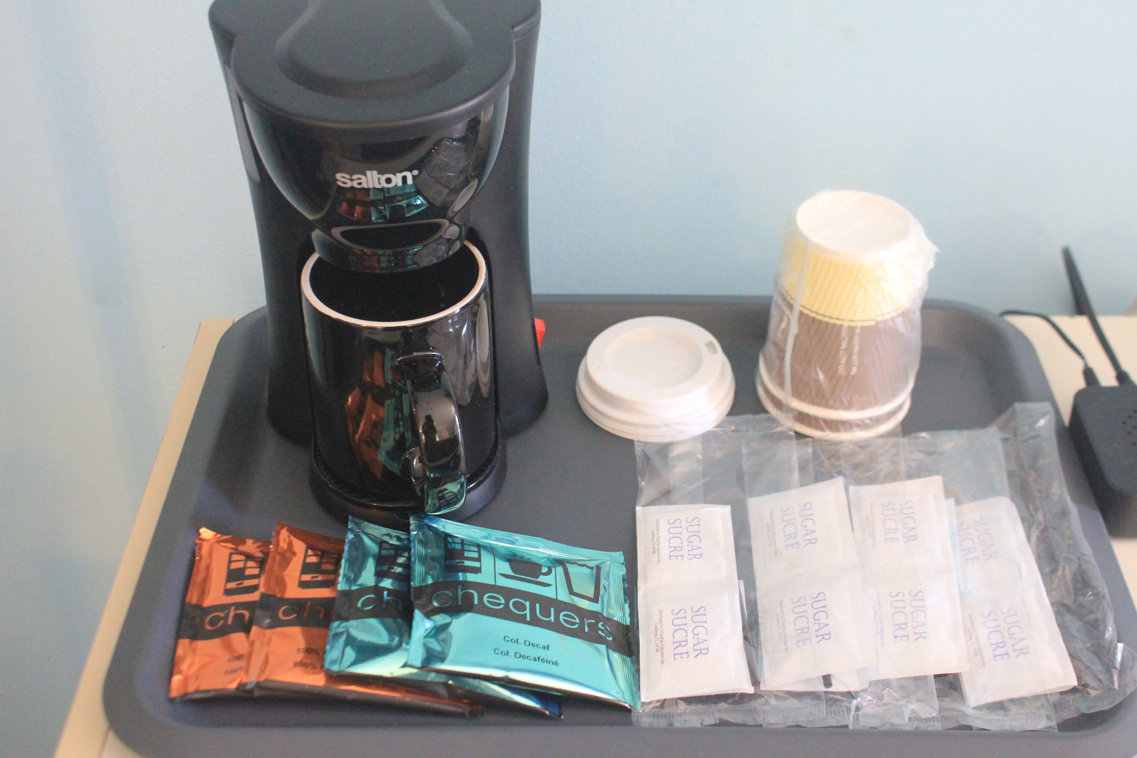 A tray with a coffee maker, sugar packets, and packets of creamer.