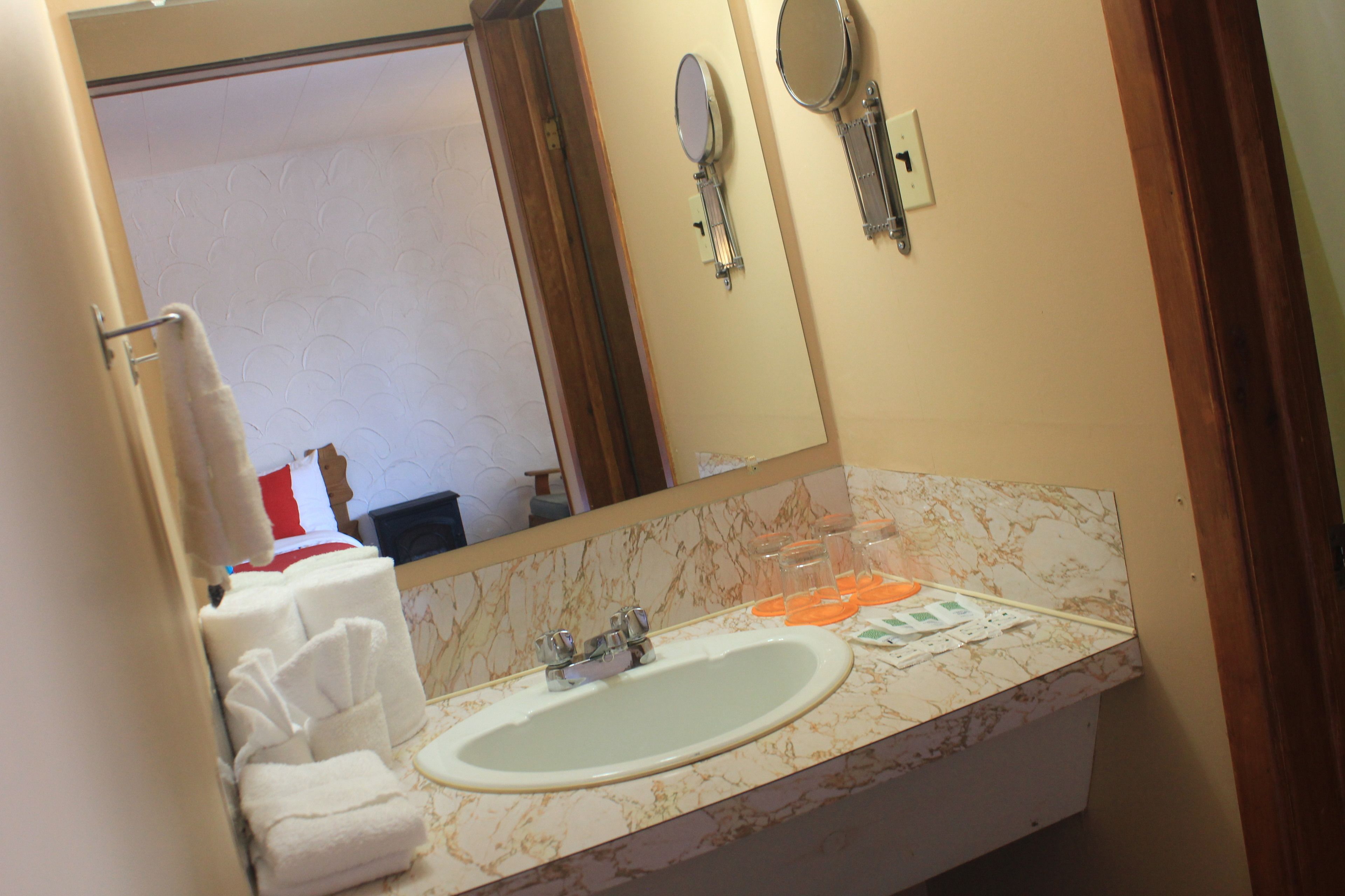 A bathroom with a sink, mirror, and towel rack.