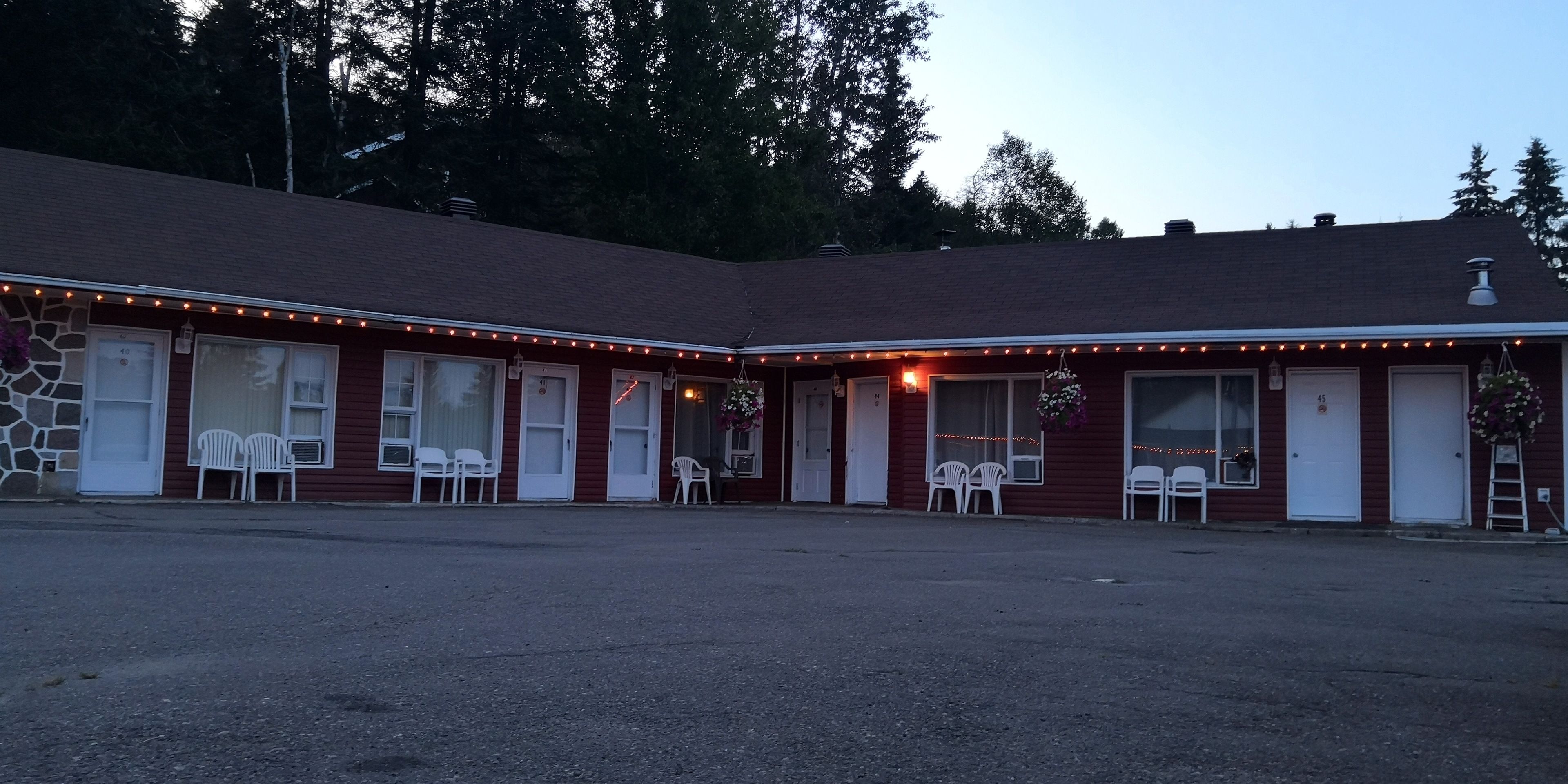 A motel with a red exterior, multiple rooms, and a parking lot.