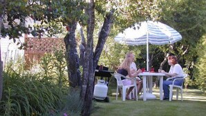 A patio with a table and chairs, surrounded by greenery and a fence. - Somass Motel (Port Alberni)
