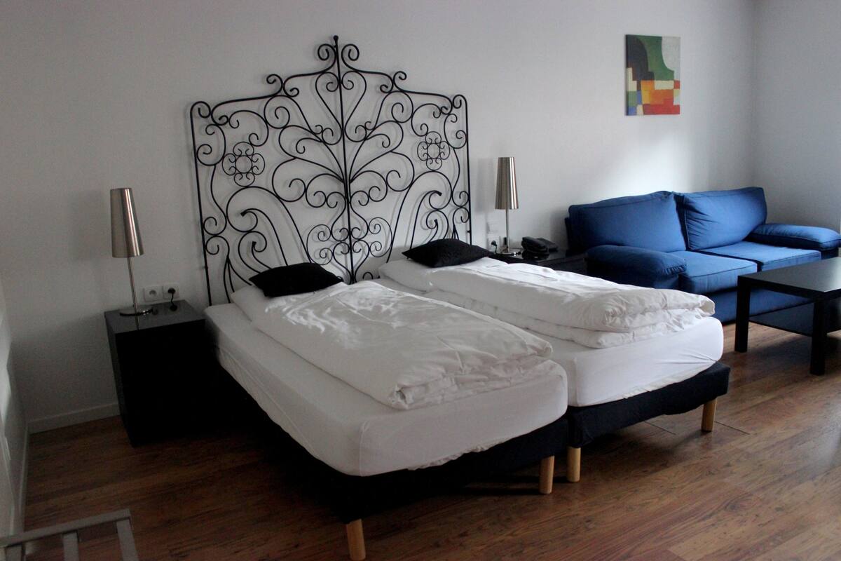 A room with a bed, a blue sofa, and a small table.