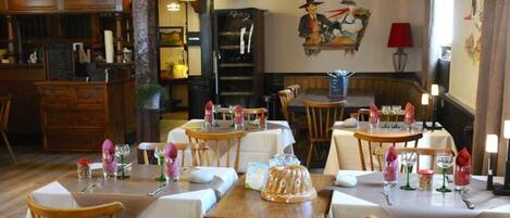 Un restaurante con mesas y sillas de madera, una zona de bar y un mural en la pared.
