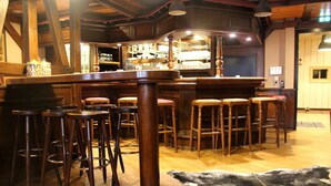 Zona de bar con taburetes de madera y mostrador.