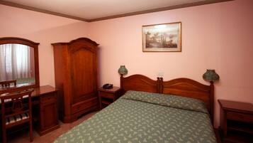 Ein Schlafzimmer mit einem hölzernen Bett, einem Schreibtisch mit Stuhl, einem Kleiderschrank und einem Nachttisch mit Lampen.