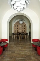 A modern dining area with a wooden wall, a chandelier, and red seating.