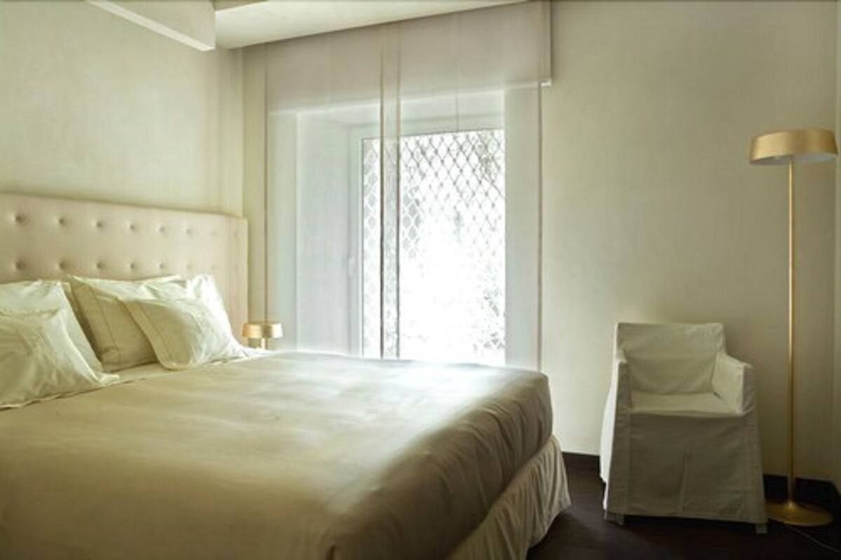 Una habitación de hotel con una cama grande, una silla y una lámpara de pie.