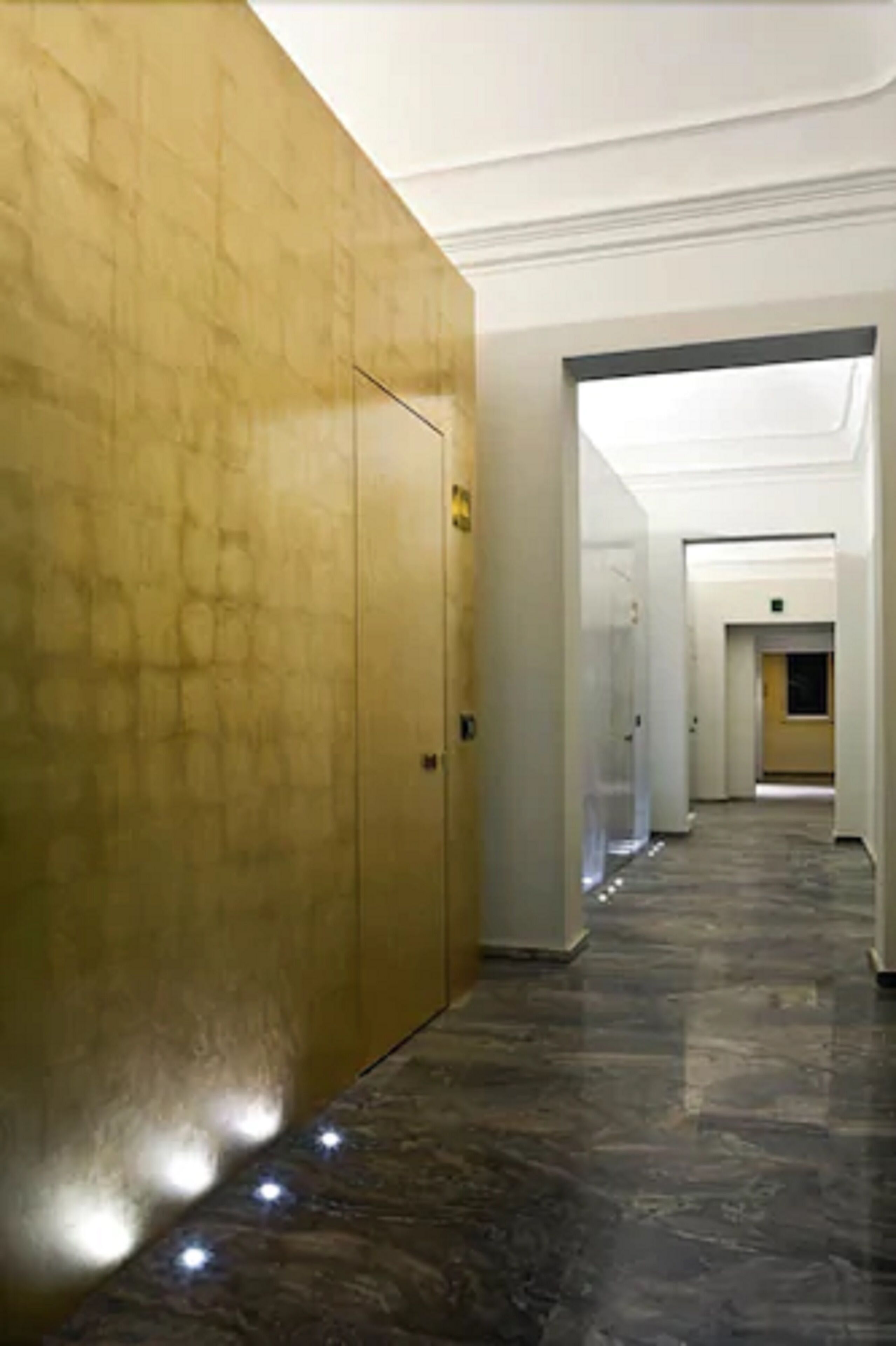 Un pasillo con suelo de mármol y pared dorada.
