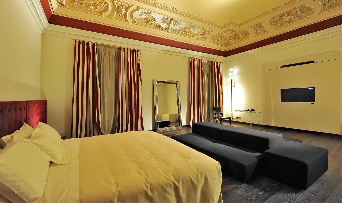Une chambre d’hôtel avec un lit, un canapé, une télévision et un miroir.