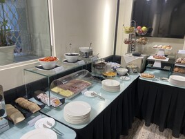 Un buffet con diversi cibi, tra cui frutta, formaggi e dolci.