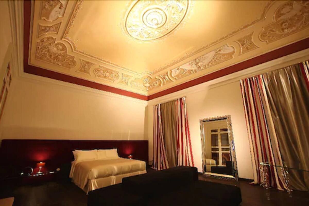 Una habitación de hotel con una cama grande, una mesita de noche, un espejo y cortinas.