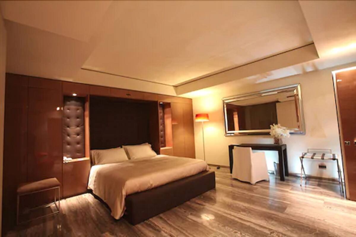 Un dormitorio moderno con una cama grande, un armario empotrado, una mesita de noche y un espejo.