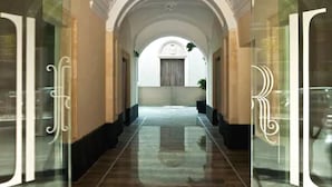 A hallway with glass doors, a tiled floor, and an arched ceiling. - Romano House (Catania)