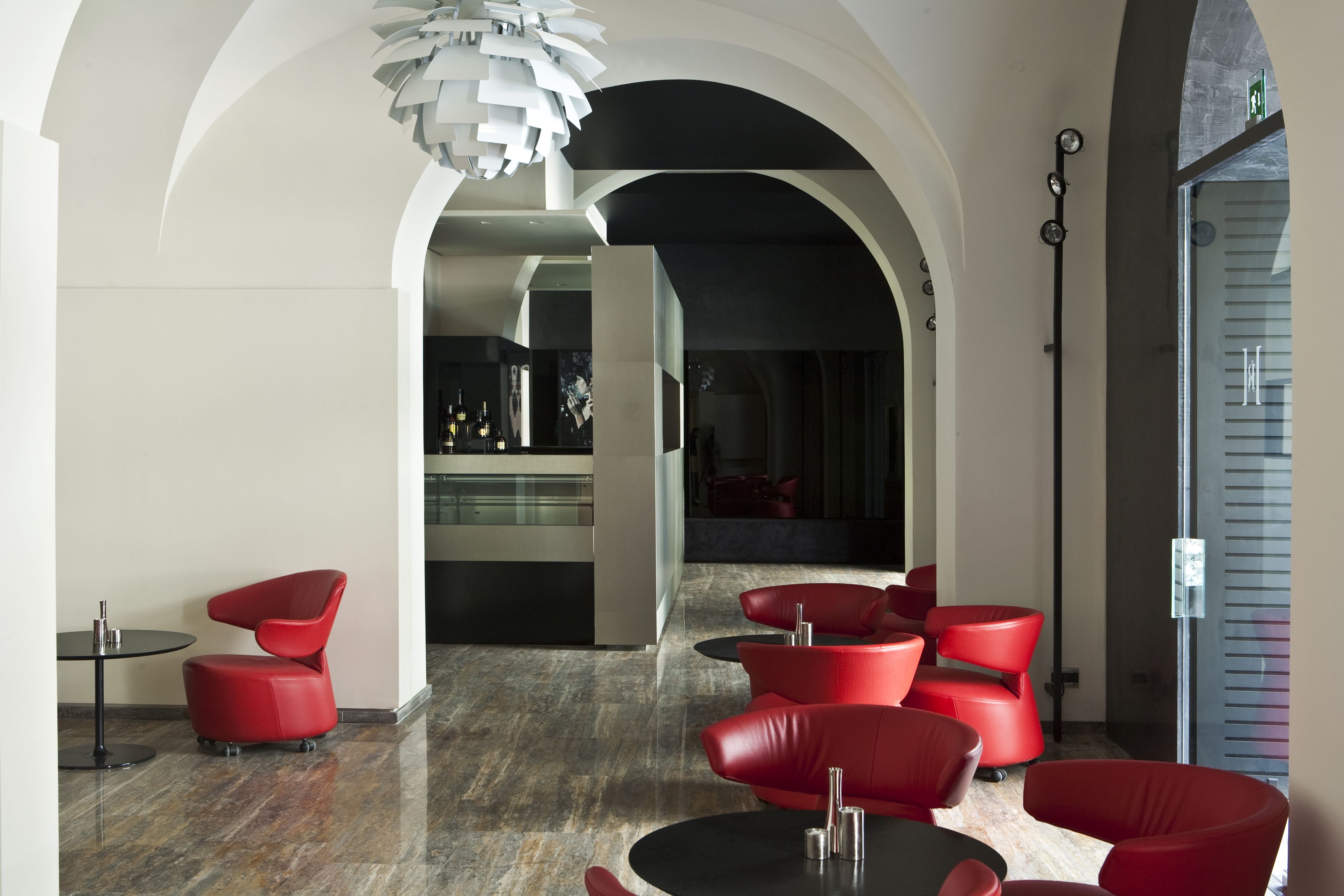 Een modern interieur met rode zitplaatsen, een glazen scheidingswand en een bijzondere plafondlamp.
