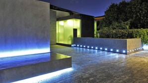 A modern outdoor area with a concrete structure, a pathway, and a well-lit entrance. - Romano House (Catania)