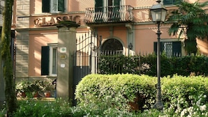 A classic hotel facade with green shutters, a wrought iron gate, and a well-maintained garden. - Classic Hotel (Florence)