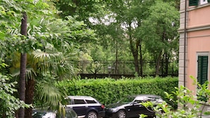 A parking area with two cars, surrounded by lush greenery and a fence. - Classic Hotel (Florence)