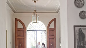 A hallway with a floral-patterned sofa, a wooden door with a glass panel, and a chandelier. - Classic Hotel (Florence)