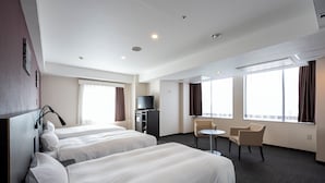 A hotel room with two beds, a desk, a chair, a television, and large windows.