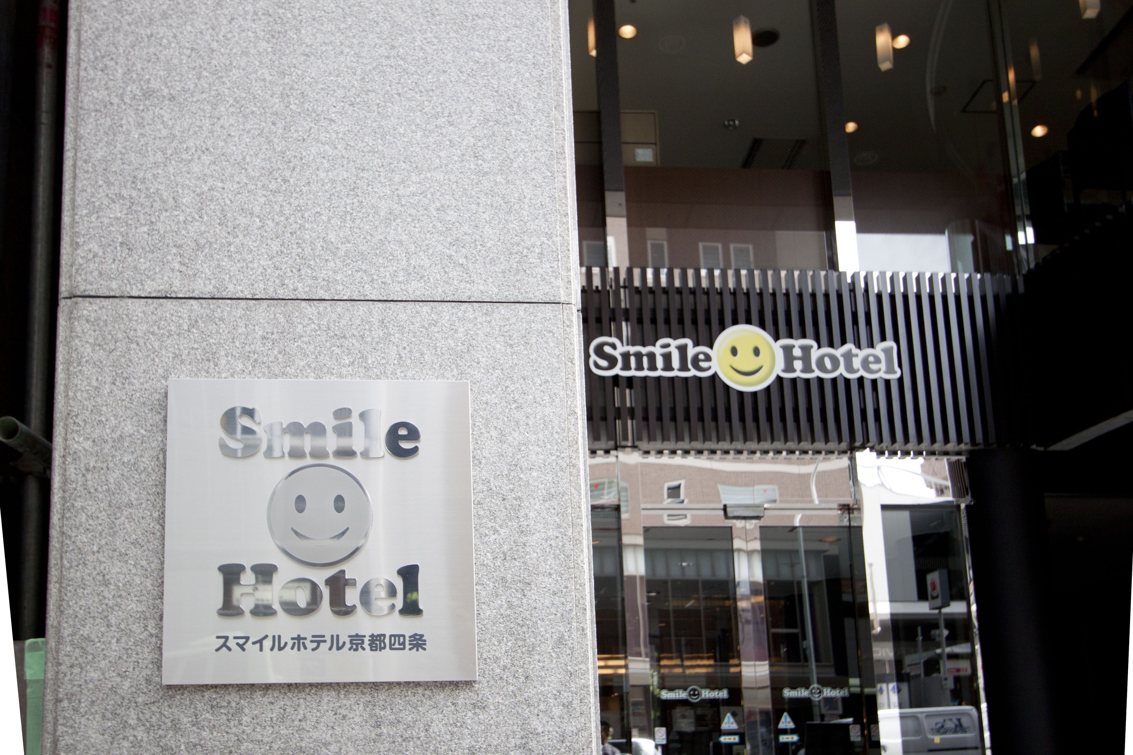A hotel sign with a smiley face logo and Japanese text.